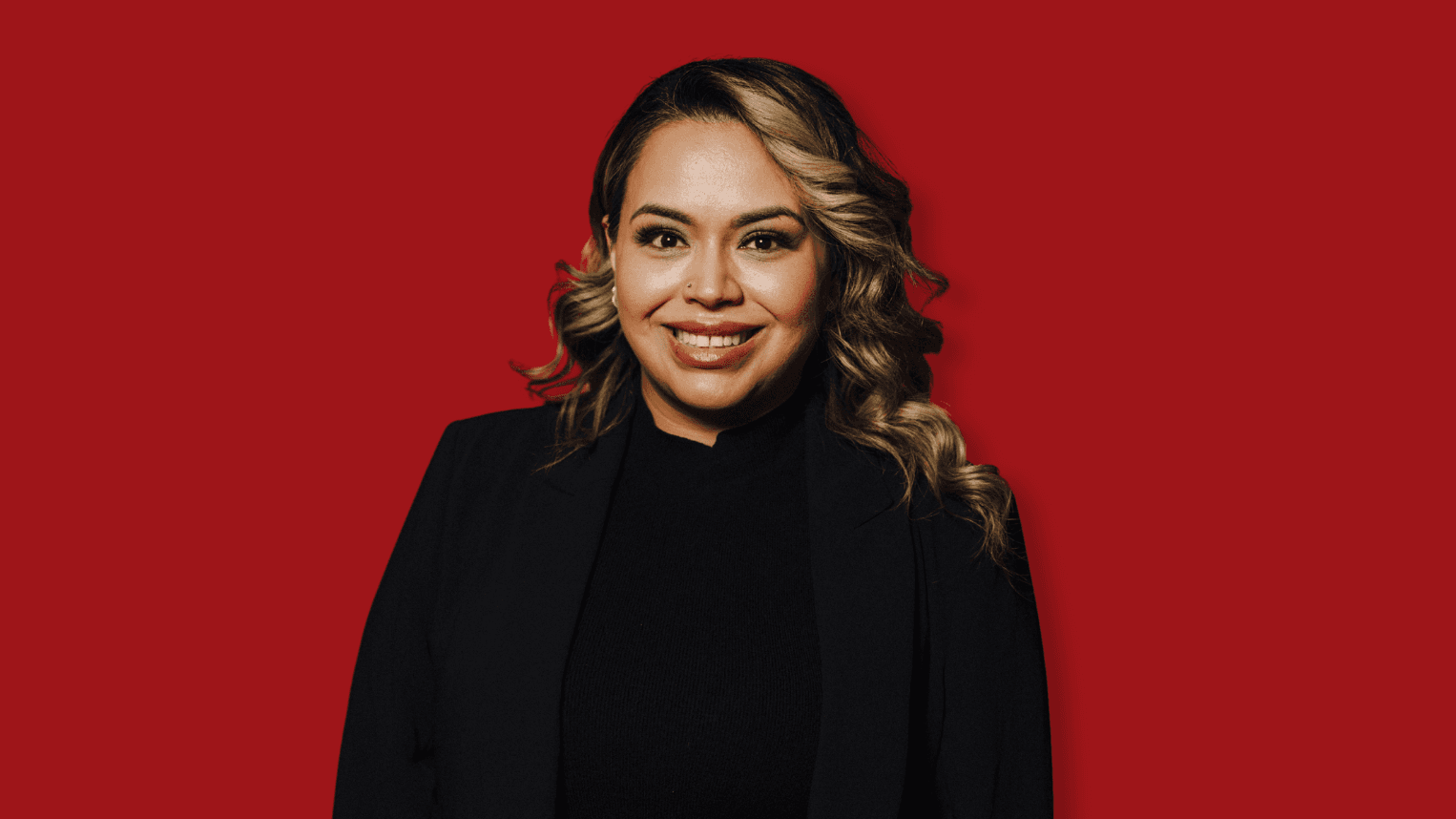 Professional woman standing in front of red background.