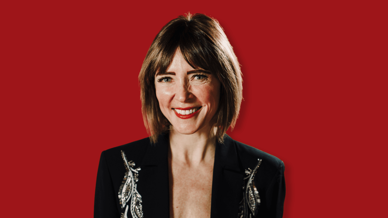Professional woman standing in front of red background.